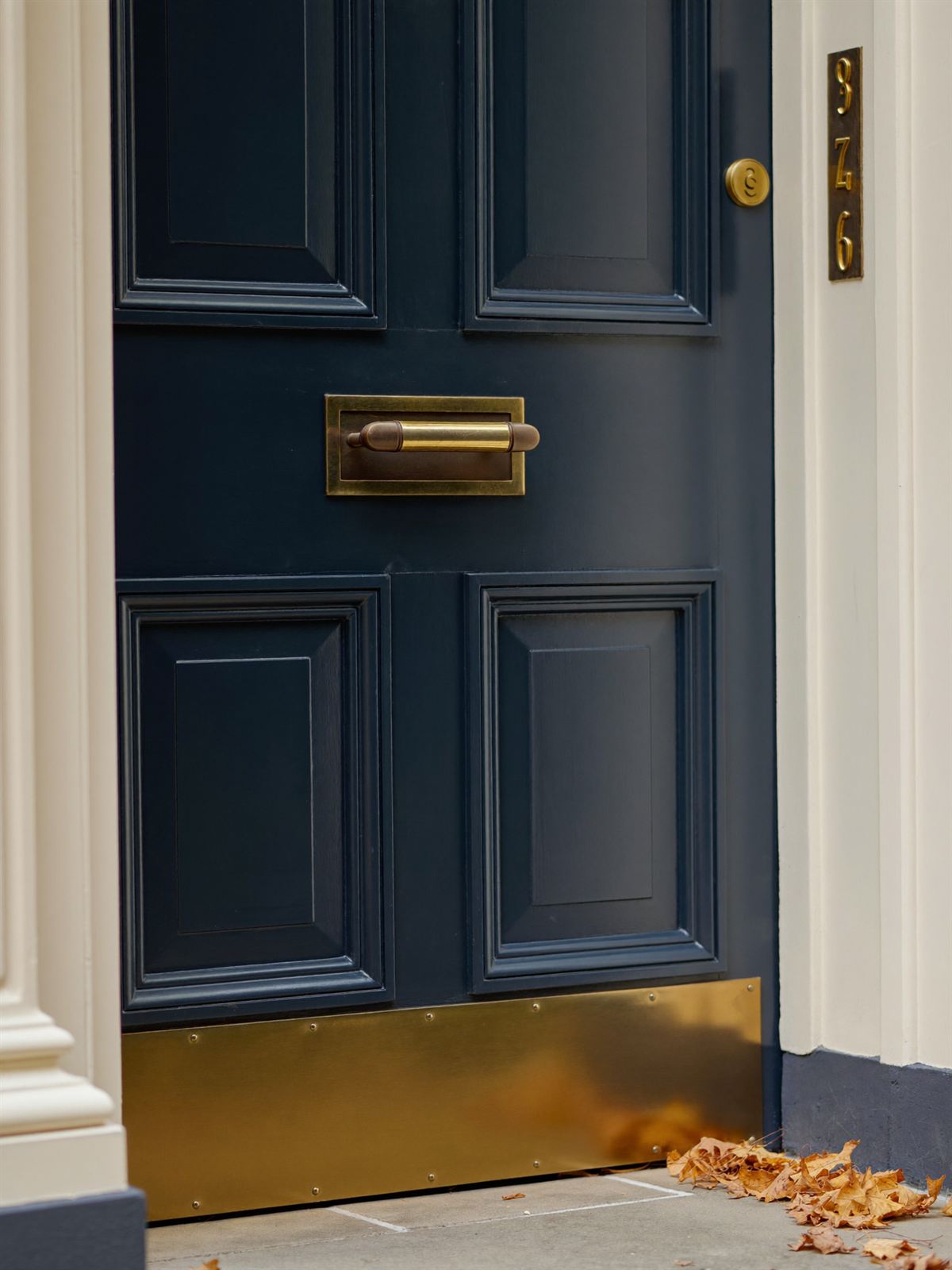 A bespoke timber front door in heritage navy with polished aged-brass furniture