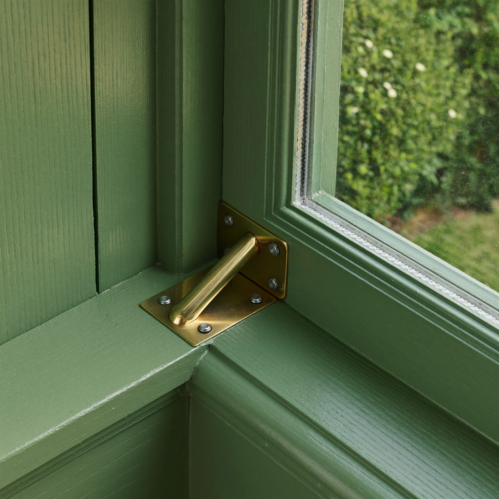 Macro detail of a freshly painted timber sash window with polished brass furniture